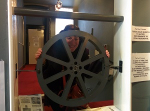 posing by the model of the Reel Cinema's logo built in as a feature of the interior by the box office